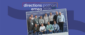 Eine Gruppe von dreizehn Personen posiert für ein Foto vor einem Hintergrund mit der Aufschrift "directions emea poznan 2025" (Wegbeschreibung emea poznan 2025) oben und einem blauen Hintergrund mit der Aufschrift "Share the future" unten.