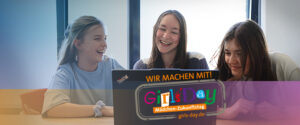 Drei Mädchen im Teenageralter sitzen zusammen, lächeln und lachen und schauen auf einen Laptop. Auf einem Banner auf dem Bild steht Wir machen mit! Girls Day - Mädchen-Zukunftstag, zum Girls Day auf girls-day.de.